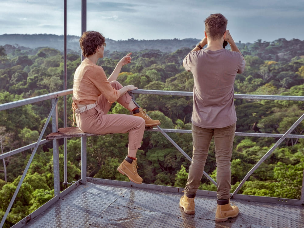 Travelers using binoculars on an observation tower high above the canopy to safely spot birds and wildlife in the Amazon Rainforest. Travelers using binoculars on an observation tower high above the canopy to safely spot birds and wildlife in the Amazon Rainforest.