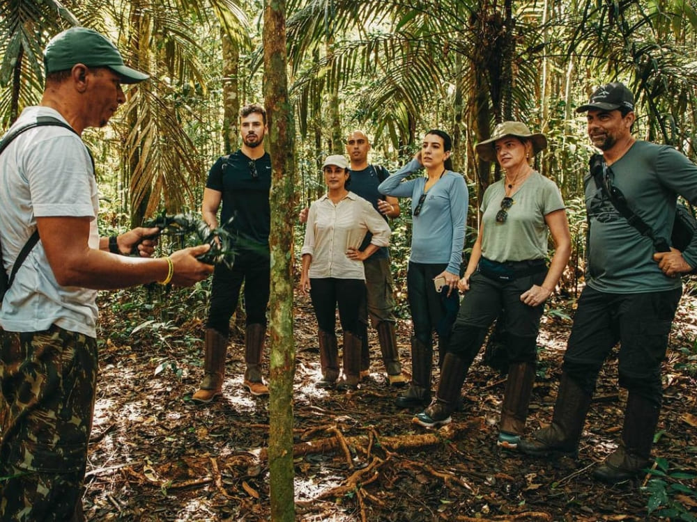 Local guide explaining the flora to a group of tourists during a jungle hiking tour in the Amazon Rainforest. Local guide explaining the flora to a group of tourists during a jungle hiking tour in the Amazon Rainforest.