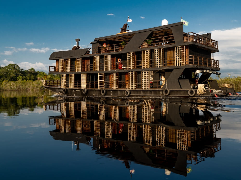 A sophisticated multi-story vessel reflects on the dark water, offering one of the best Amazon river cruises in Brazil. A sophisticated multi-story vessel reflects on the dark water, offering one of the best Amazon river cruises in Brazil.