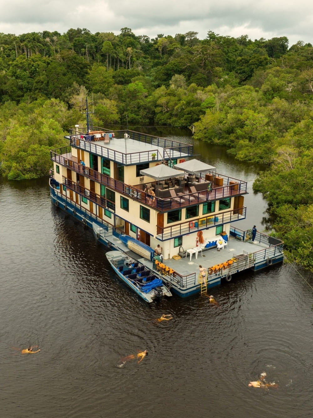 Aerial view of the La Jangada riverboat docked near the jungle, showcasing its spacious upper deck and proximity to the rainforest nature. Aerial view of the La Jangada riverboat docked near the jungle, showcasing its spacious upper deck and proximity to the rainforest nature.