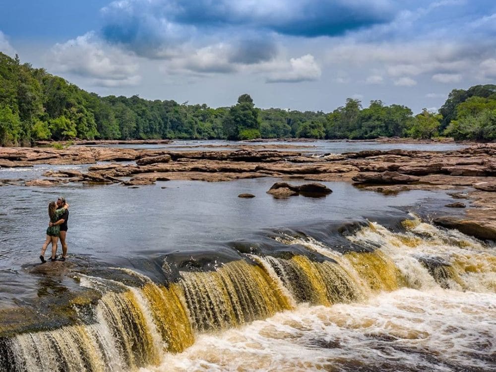 Couple hugging in the shallow waters of river rapids surrounded by forest in the Jaú National Park.