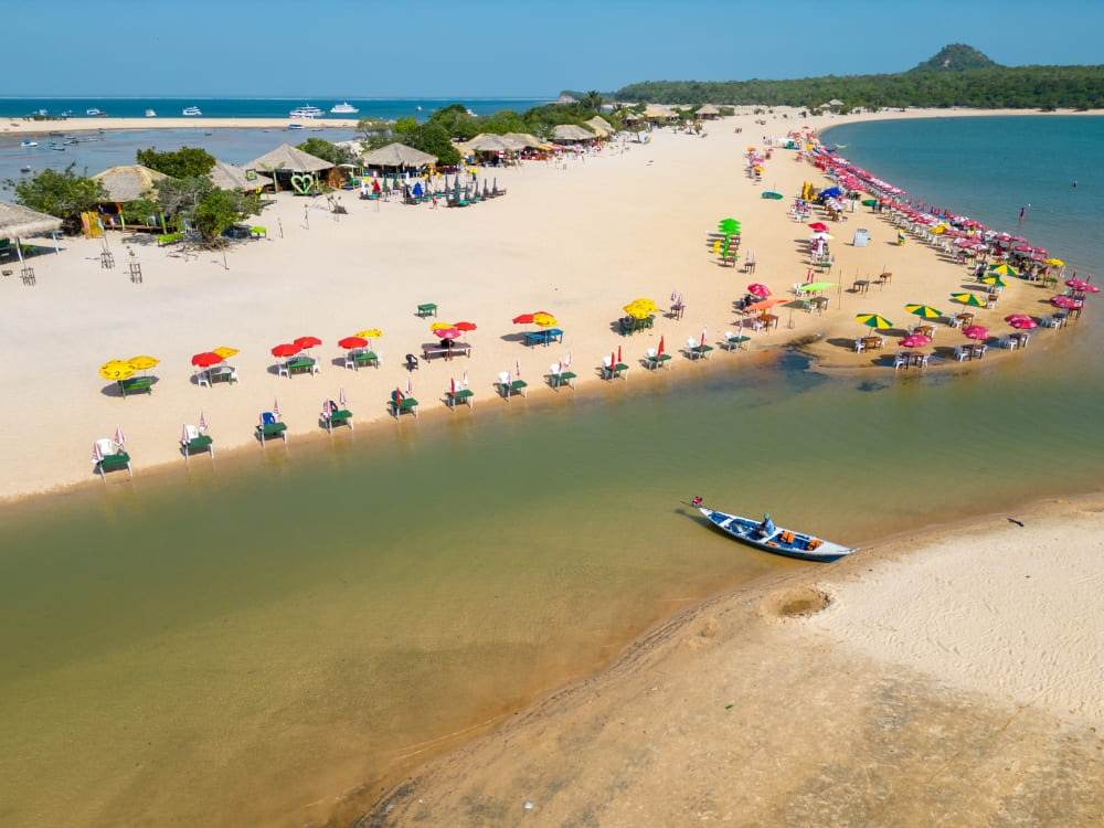 White sand beach filled with colorful umbrellas along the greenish waters of the Tapajós River in Alter do Chão.