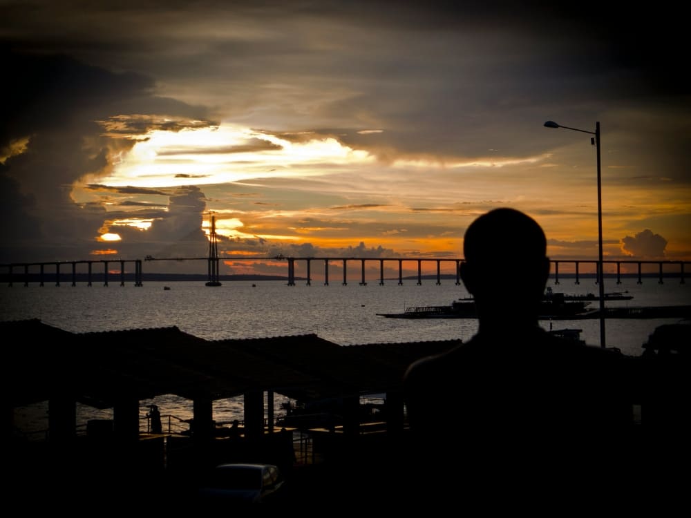 Silhouette of a traveler watching the sunset over the Amazon River from Manaus, the gateway to the rainforest. Silhouette of a traveler watching the sunset over the Amazon River from Manaus, the gateway to the rainforest.