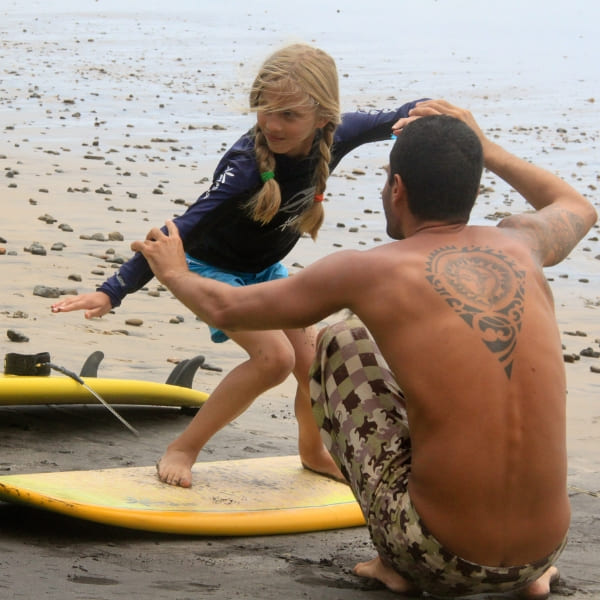 Criança em aula de surfe na praia de Itacaré, Bahia, Brasil.