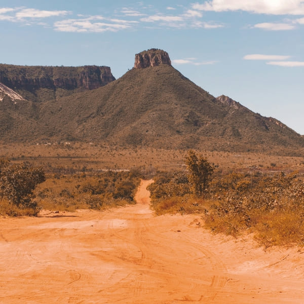 Estrada de terra vermelha cortando o Cerrado em direção a uma serra de topo plano no Jalapão, Tocantins, Brasil.