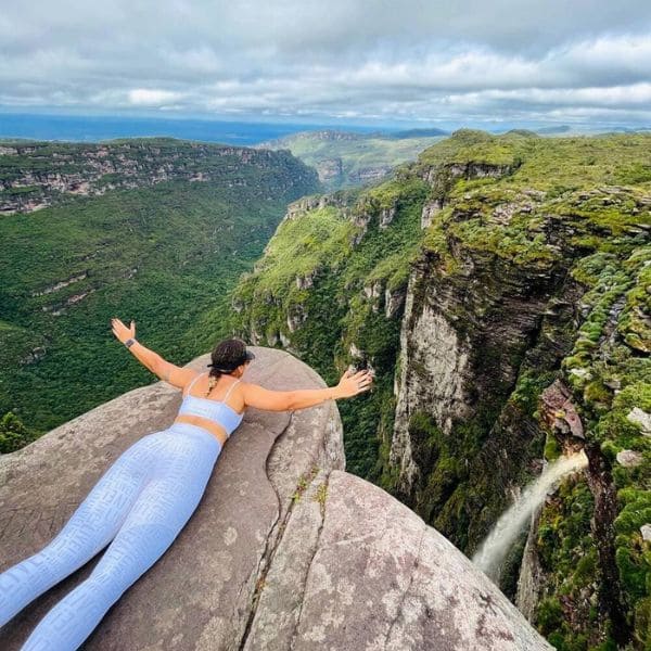 Trilheira deitada na beira do mirante do Cachoeirão, de braços abertos sobre o cânion do Vale do Pati, na Chapada Diamantina, Brasil.
