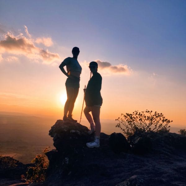 Dois trilheiros em silhueta sobre uma pedra ao pôr do sol, na Chapada Diamantina, Brasil.