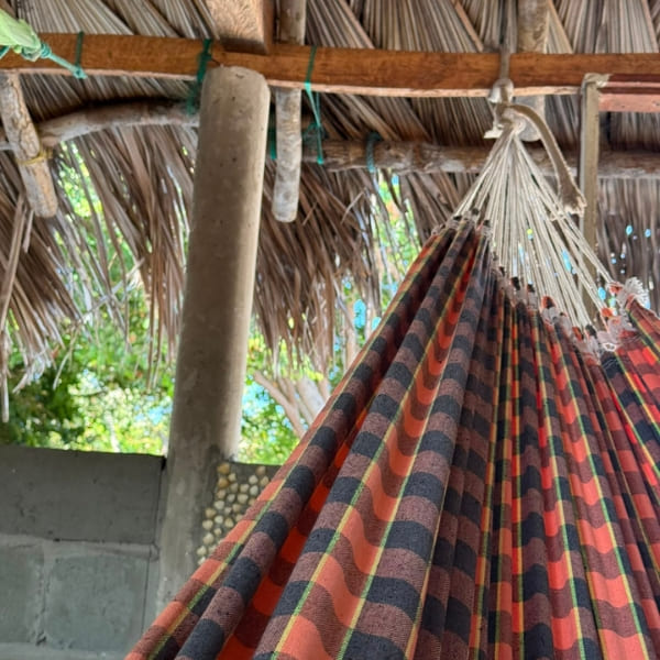Hamaca a rayas colgada bajo un techo de paja, la cama típica del trekking por los Lençóis Maranhenses