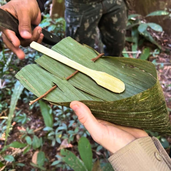 Guia mostrando um prato e uma colher feitos na hora com folha de palmeira durante uma caminhada na selva amazônica